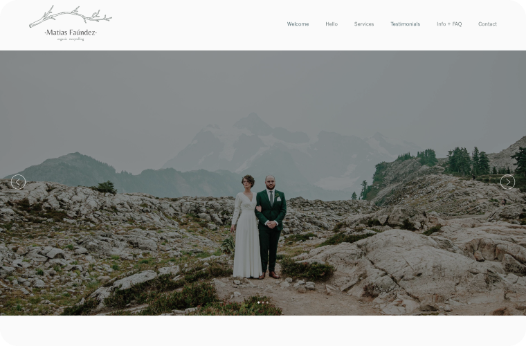 Couple in wedding attire posing on rocky mountaintop, mountains in background