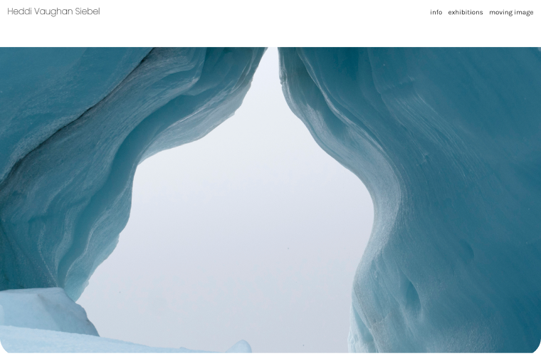 Ice cave opening, viewed from below; blue-tinged ice walls curve upwards against a hazy sky